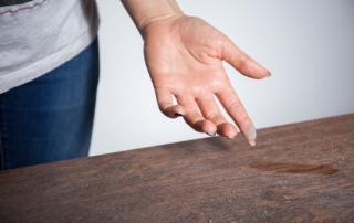 Lady wiping a finger across a dusty table