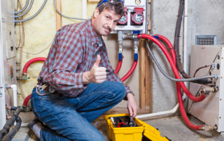 Happy handyman showing thumbs up while working on a furnace.